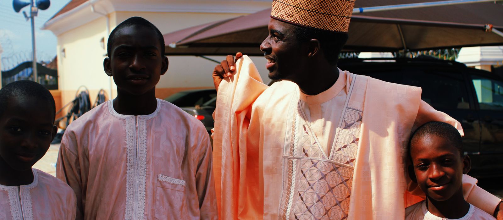 A Nigerian father in traditional dress with his children outside the family home