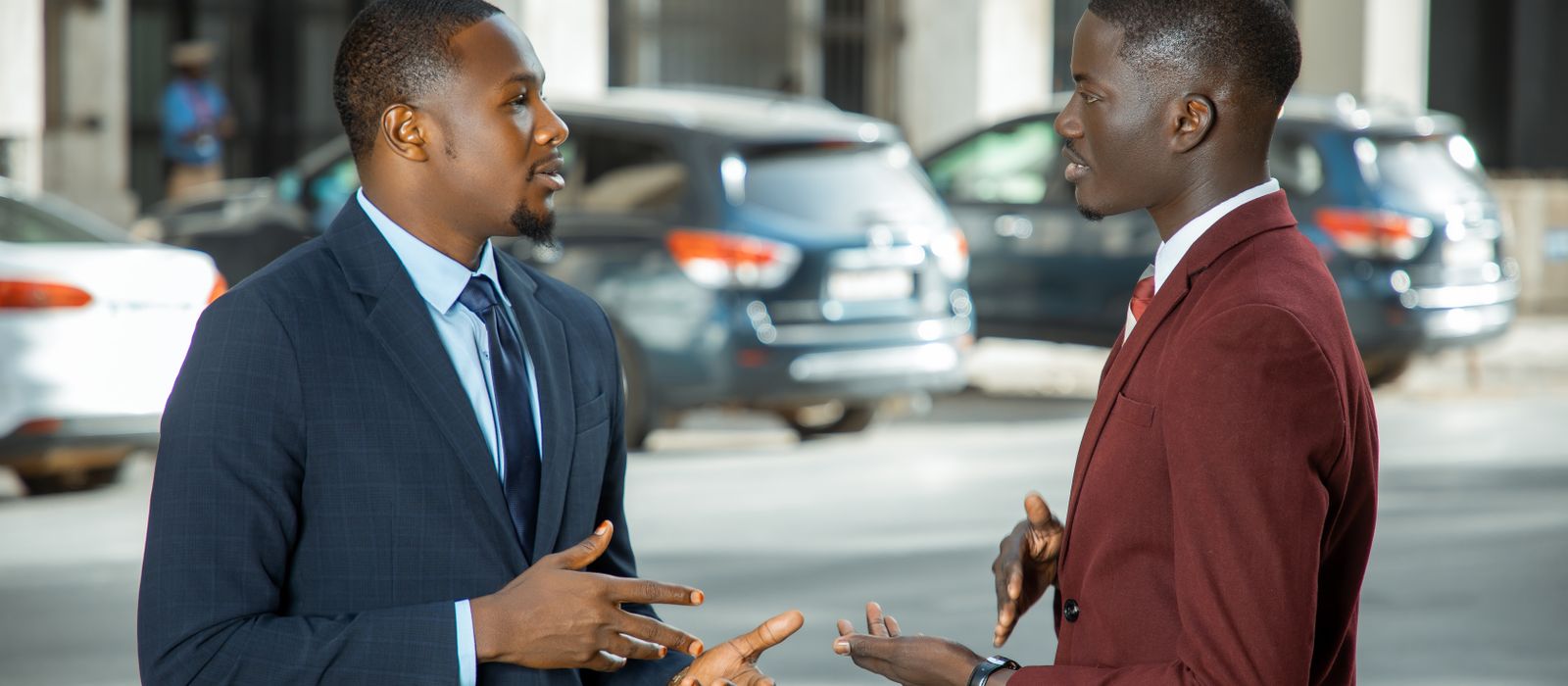 Two African professionals in suits talking on a city street