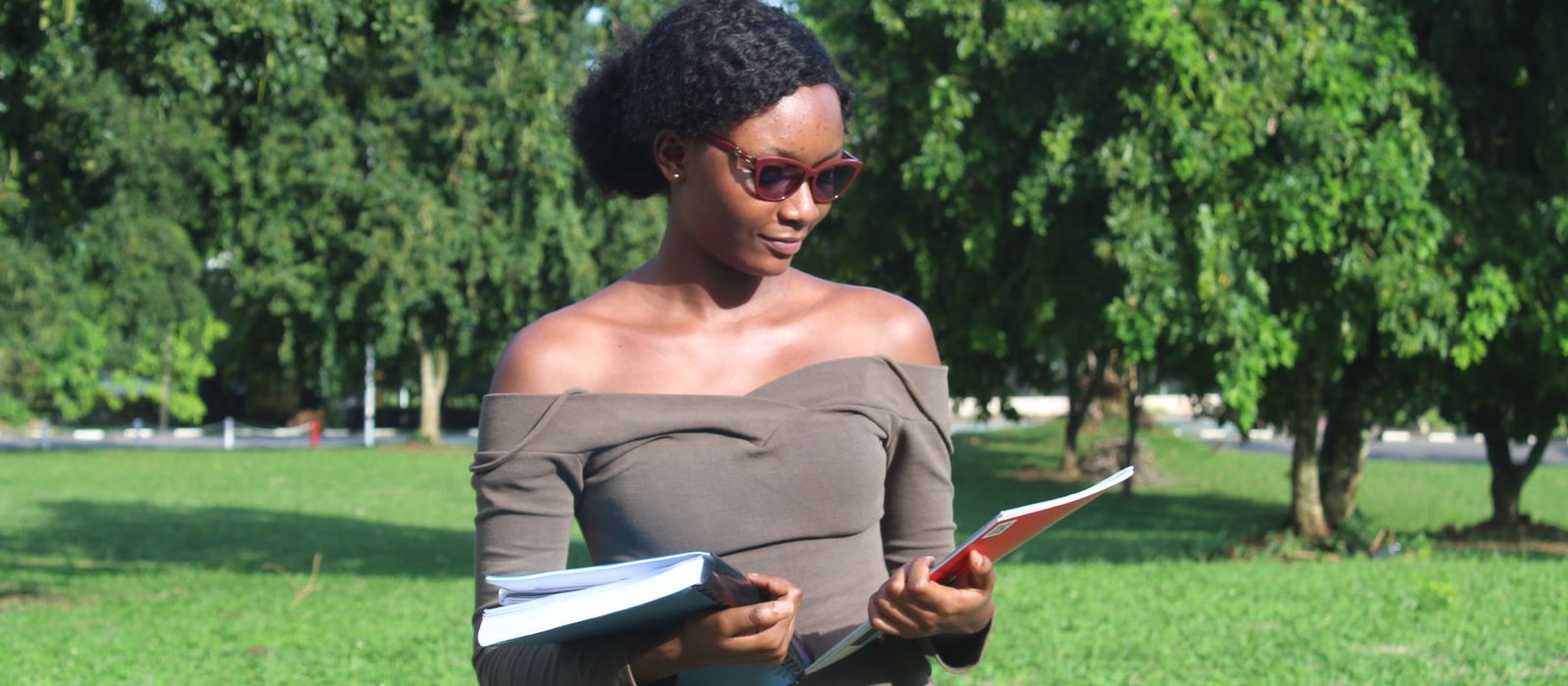 A young African woman studying outdoors with a book
